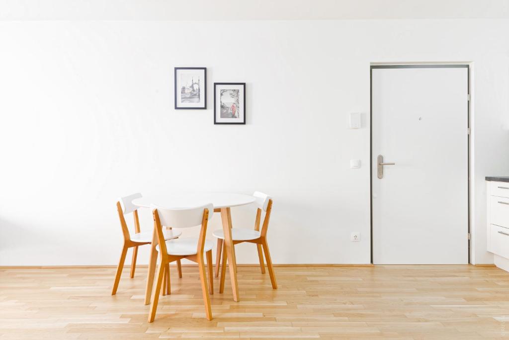 einen Esstisch und Stühle in einem weißen Raum in der Unterkunft Whats-App Self-Check-IN - 1BR Apartment, near airport,15 min to Center in Wien