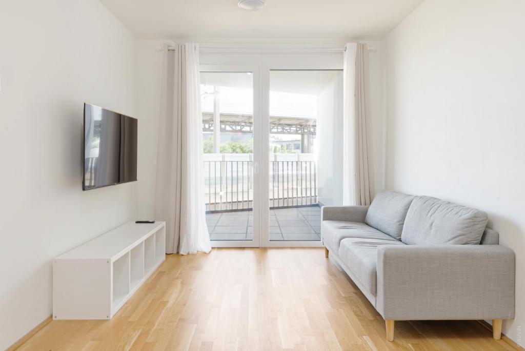 ein Wohnzimmer mit Couch und Fernseher in der Unterkunft Whats-App Self-Check-IN - 1BR Apartment, near airport,15 min to Center in Wien