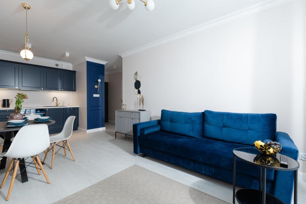 ein Wohnzimmer mit einem blauen Sofa und einer Küche in der Unterkunft Apartament Liliowy by Major Domus Club in Dziwnów