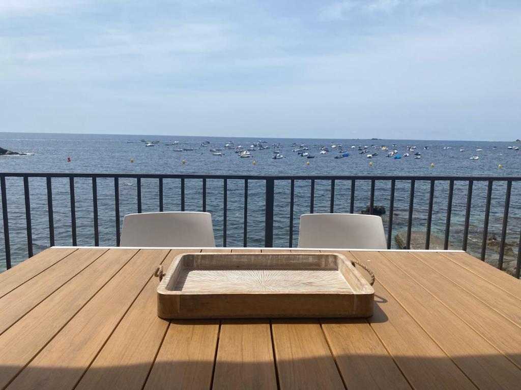 una mesa de madera con sillas y vistas al agua en Playa Canadell MAR G primera linea de mar con terraza, en Calella de Palafrugell