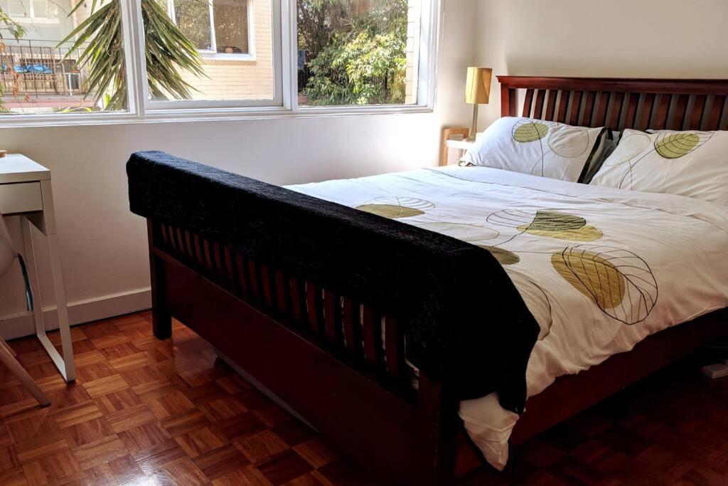 a bedroom with a bed with a wooden frame and a window at Elwood Beach Apartment (2 min walk from beach) in Melbourne