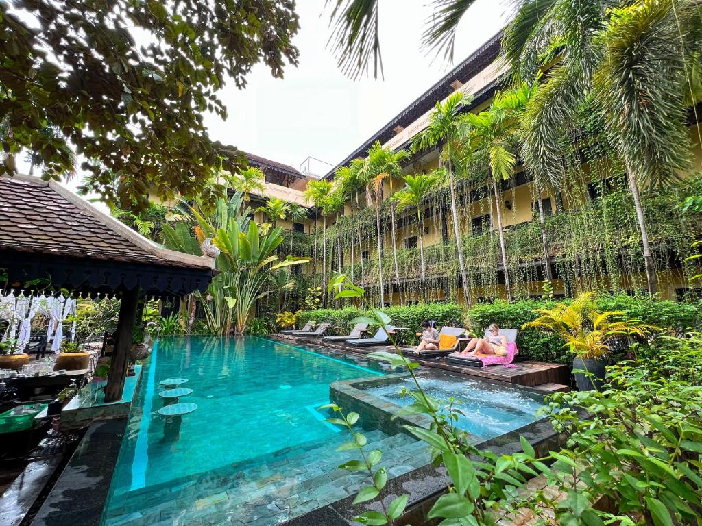 a swimming pool in a building with two people sitting next to it at Residence Indochine Suite in Siem Reap