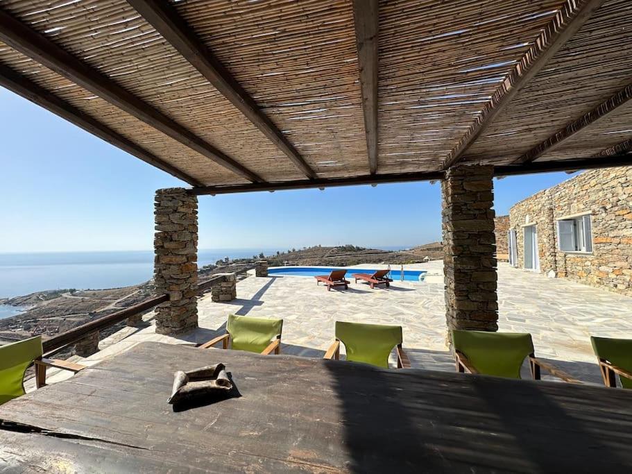 una mesa y sillas en un patio con vistas al océano en Divine Blue Villa Nano in Koundouros Kea Cyclades with pool and sea view, en Koundouros