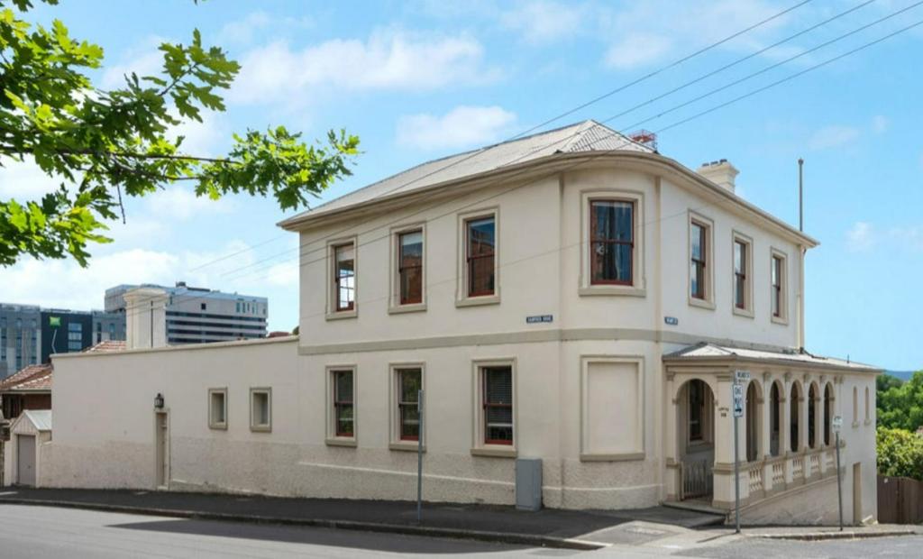 an old white building on the corner of a street at Lumeah - Servant Quarters in Hobart