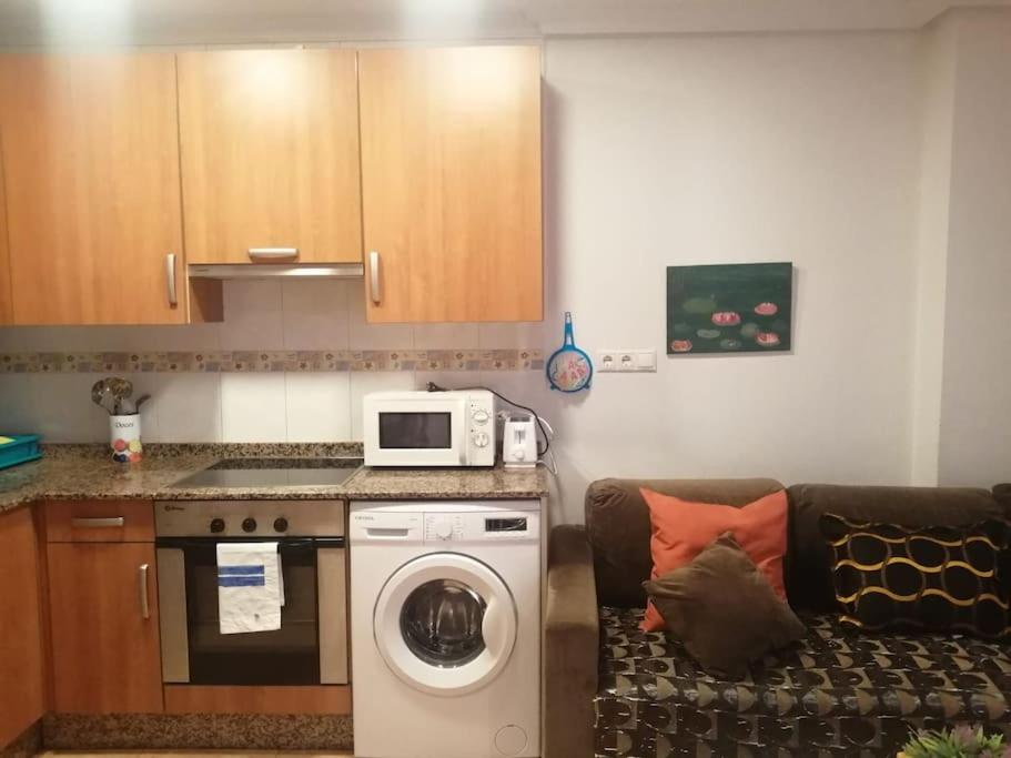 a kitchen with a washing machine and a microwave at Apartamento con terraza a 800 m playa in Gijón