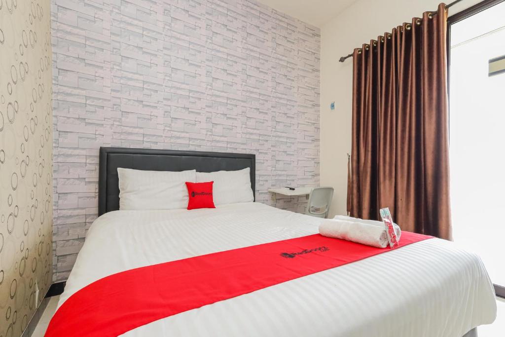 a bedroom with a large white bed with red pillows at RedDoorz Syariah near Green Park Jatiwarna in Bekasi