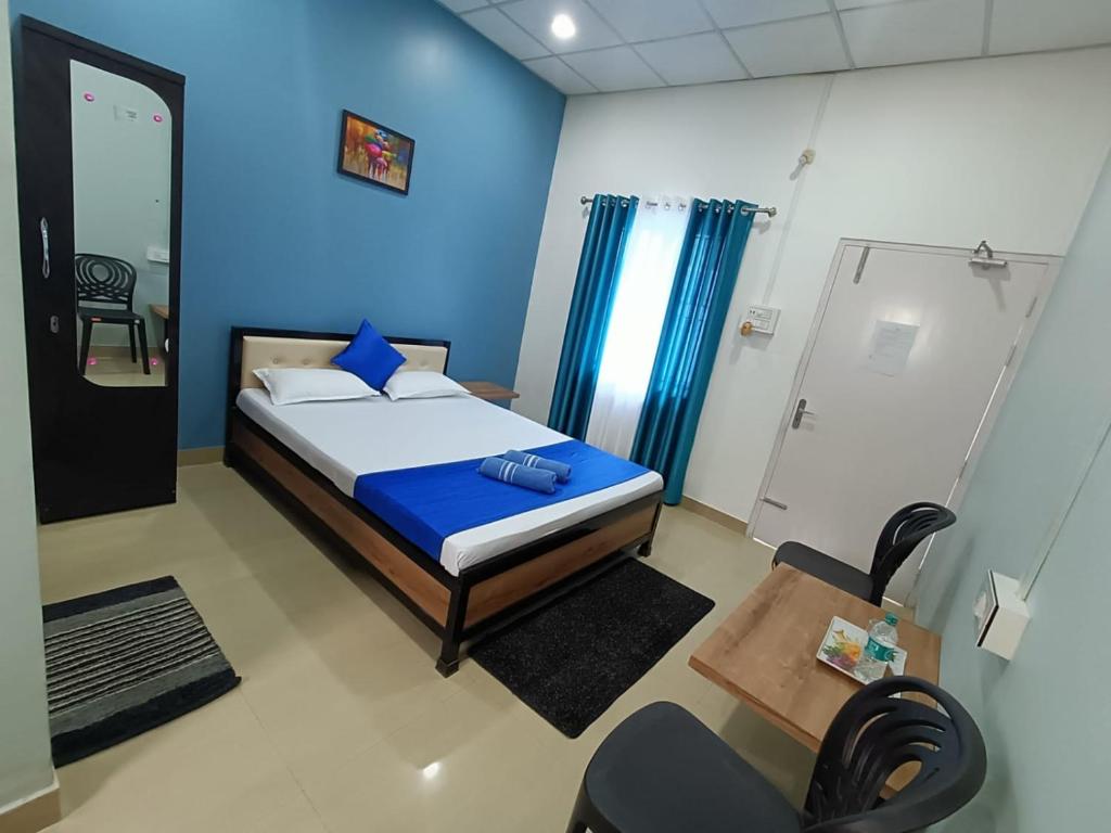 sypialnia z łóżkiem i niebieską ścianą w obiekcie The Corner Inn (Lodge) w mieście Guwahati