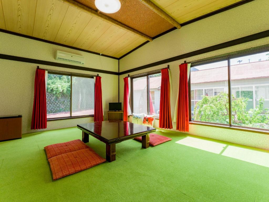 ein Wohnzimmer mit einem Tisch und einigen Fenstern in der Unterkunft Yuraku Izu-Oshima - Vacation STAY 44725v in Oshima