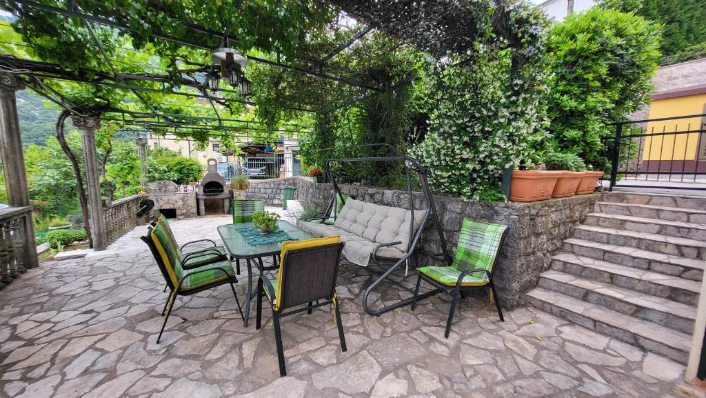 a patio with a table and chairs and a stone wall at Apartment Capt Seferovic 2 in Donji Morinj