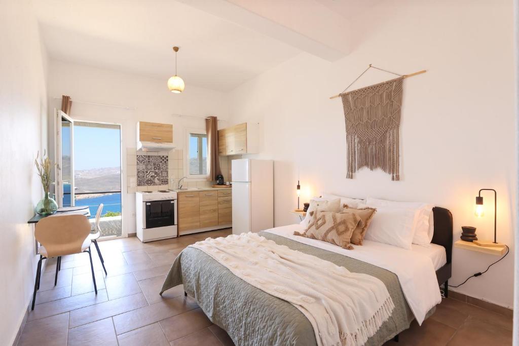 a white bedroom with a large bed and a kitchen at ēnNĒ Studios for Views & Tranquility in Elia
