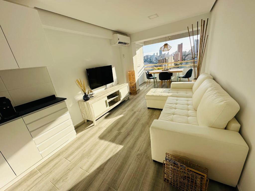 sala de estar con sofá blanco y TV en Sorolla Views Benidorm, en Benidorm