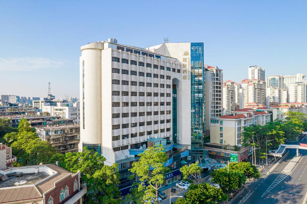 een hoog wit gebouw in een stad met gebouwen bij Cheng Bao Hotel Shantou Mixc Branch in Shantou