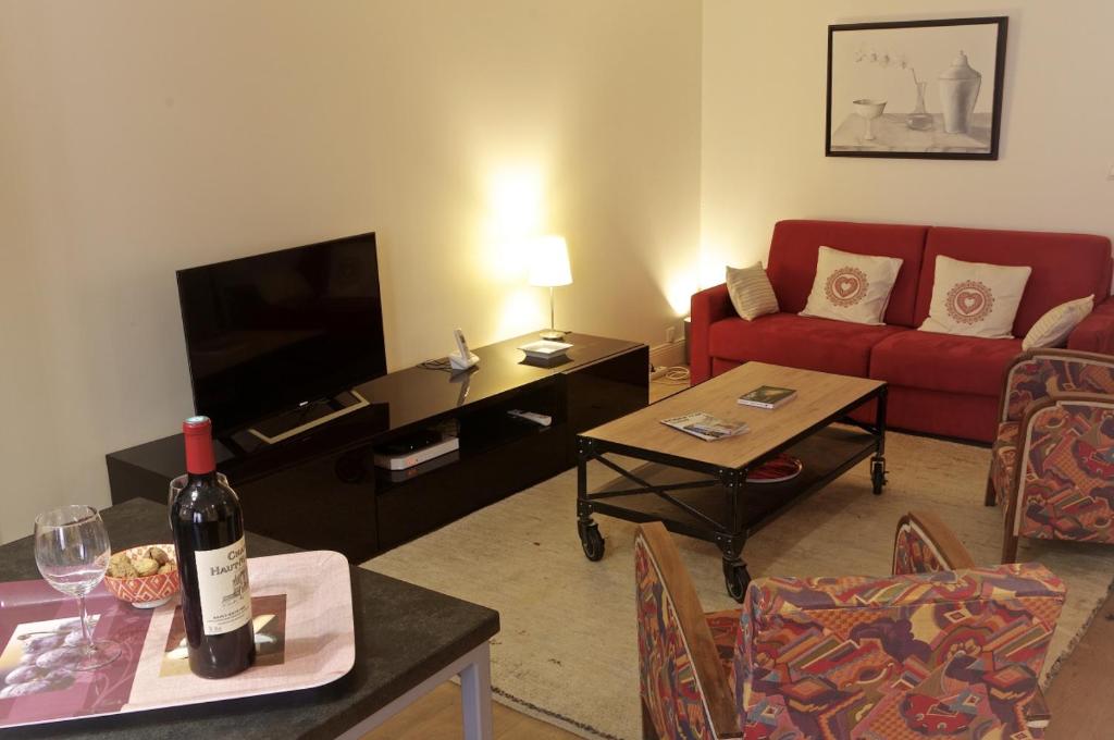 ボルドーにあるSauvageau - Appartement 1 chambre avec Parkingのリビングルーム(赤いソファ、ワインボトル付)