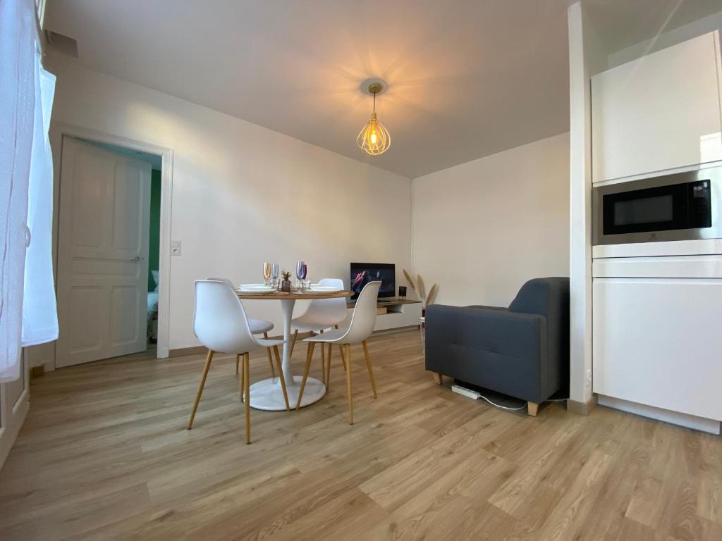 ein Wohnzimmer mit einem Tisch, Stühlen und einem Sofa in der Unterkunft Appartement luxueux rénové avec balcon & garage in Troyes
