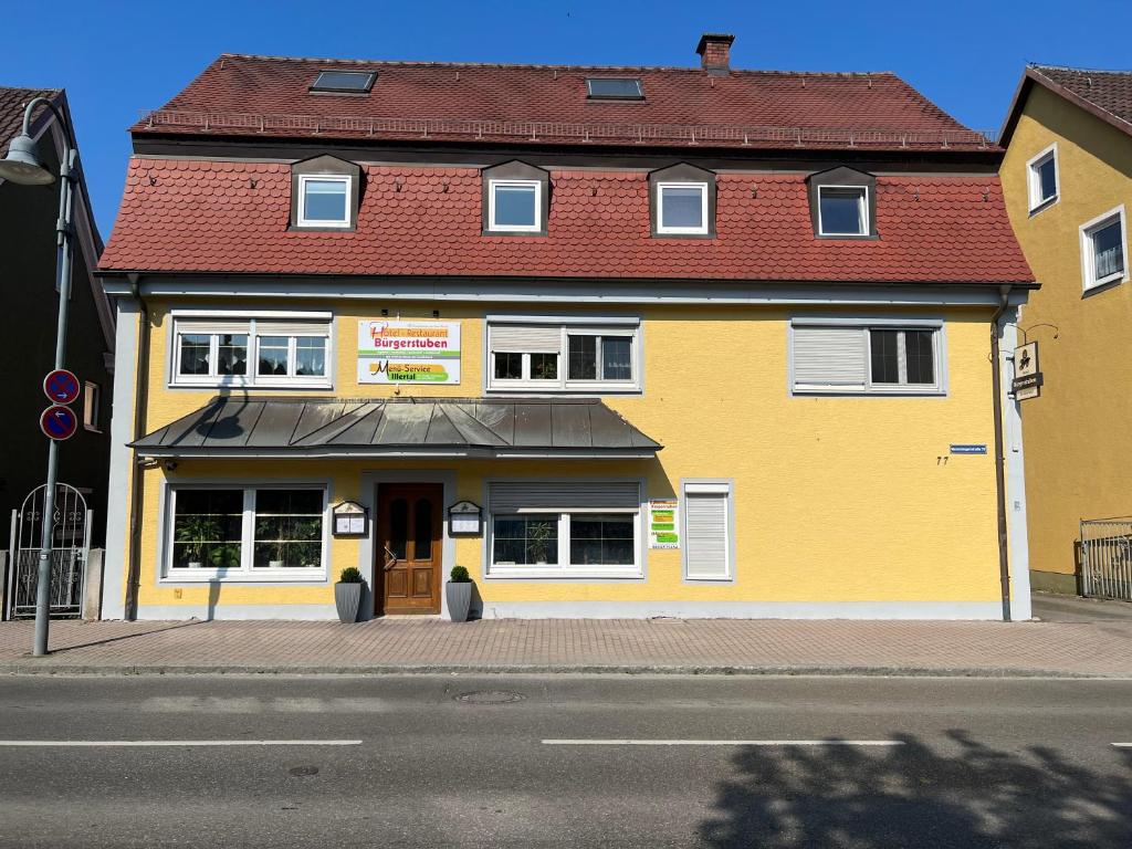 un edificio amarillo con techo rojo en una calle en Hotel Restaurant Bürgerstuben, en Altenstadt