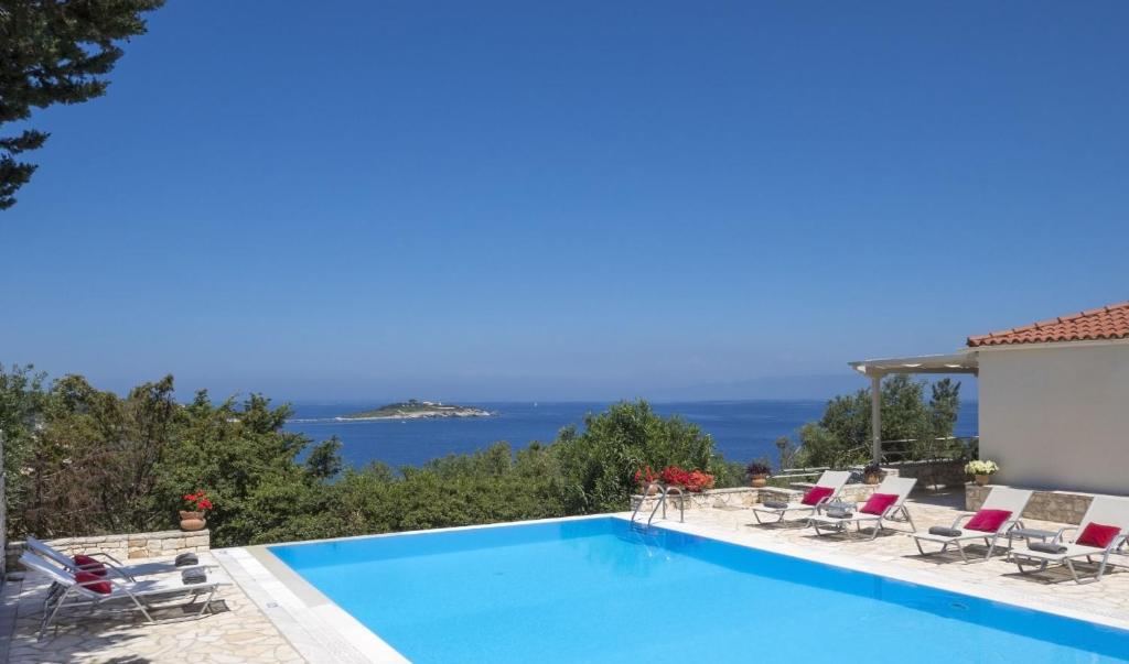 una piscina con sillas y vistas al océano en Villa Flora, en Oziás