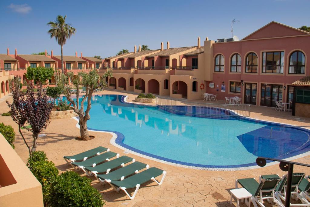 uma piscina com espreguiçadeiras e um resort em Grupoandria Aparthotel Club Andria em Cala Santandria