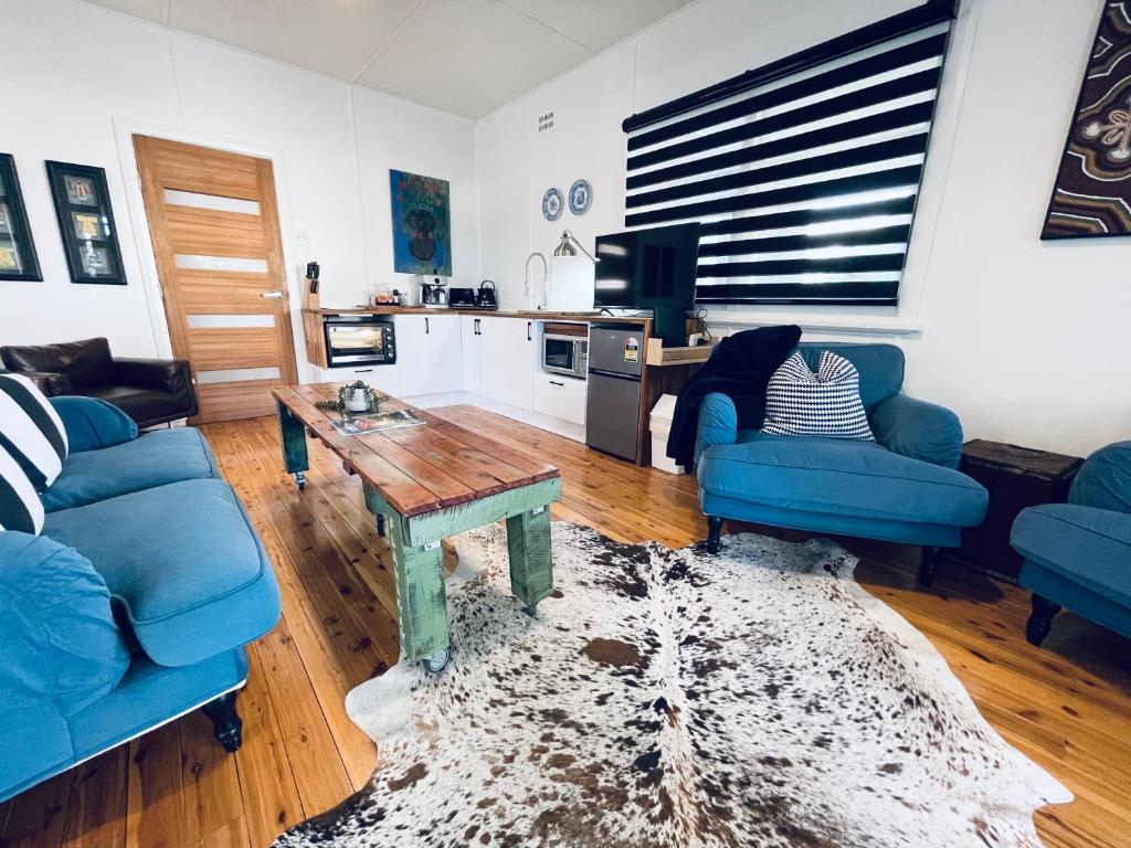a living room with two blue couches and a table at Town Cottage in Tenterfield