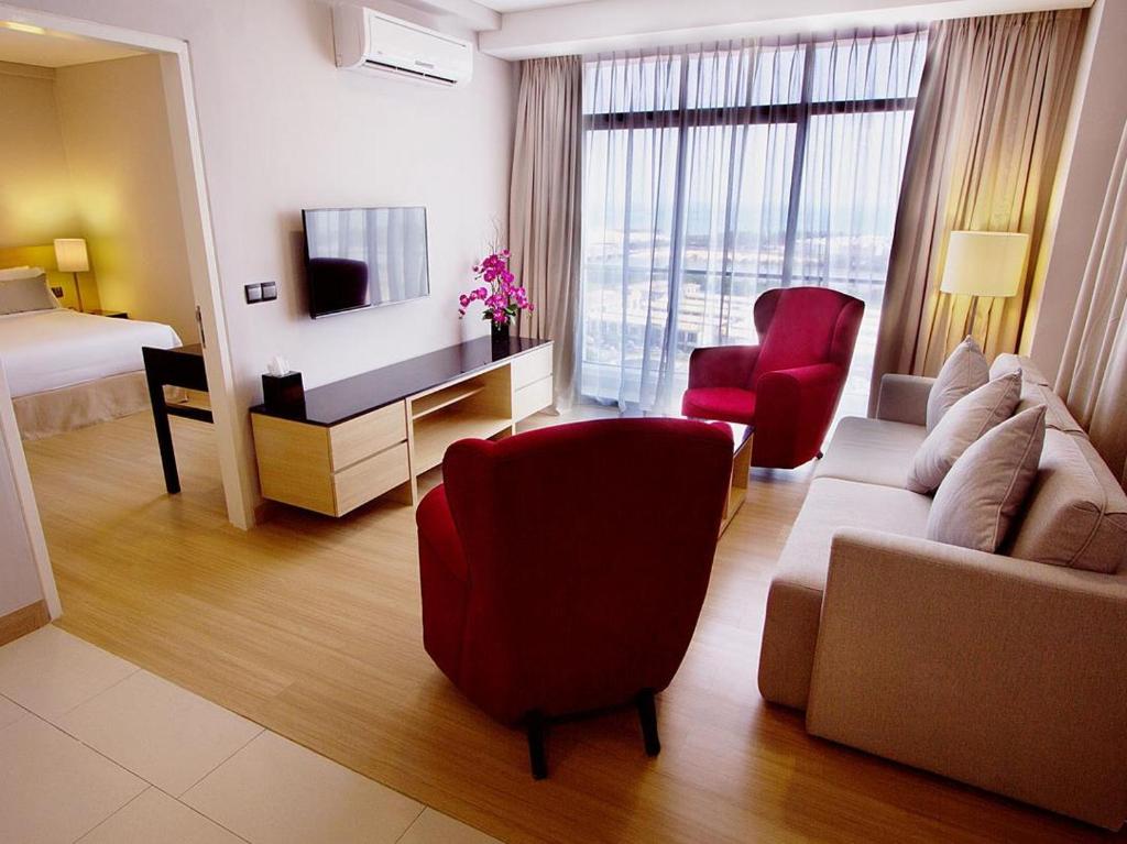 ein Hotelzimmer mit einem Wohnzimmer mit einem Sofa und einem Stuhl in der Unterkunft The Straits Hotel & Suites in Malakka