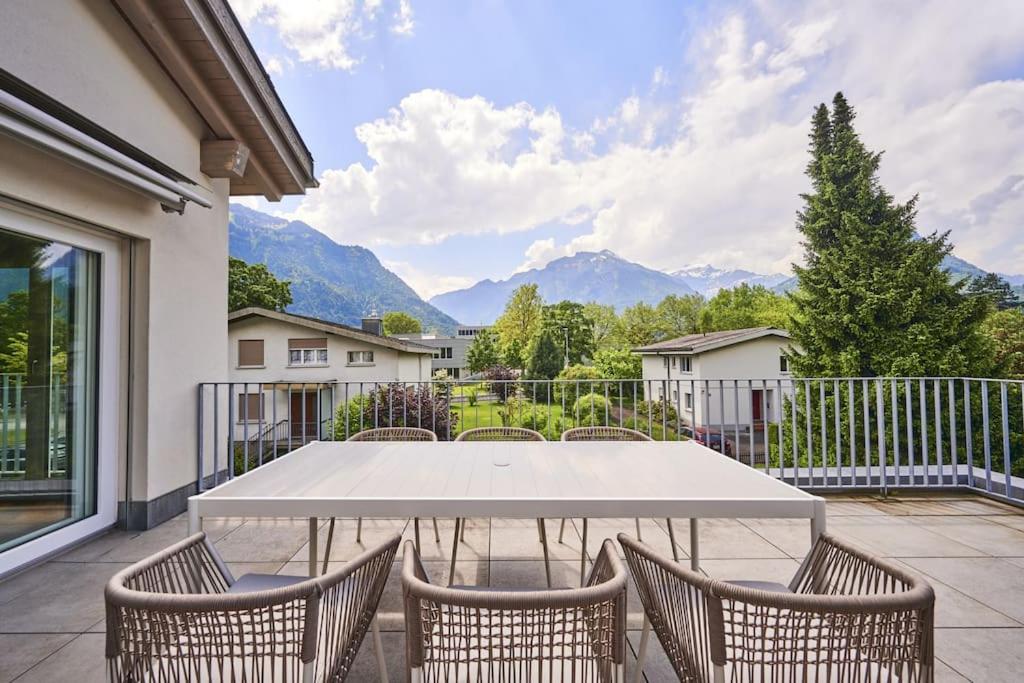 a white table and chairs on a patio with mountains at Terrace Vista Interlaken in Interlaken