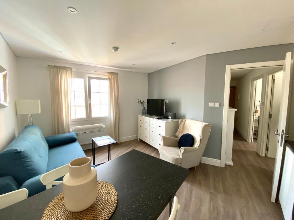 a living room with a blue couch and a table at Deluxe City Centre Two Bedroom with Private Balcony - Grand Central House in Gibraltar