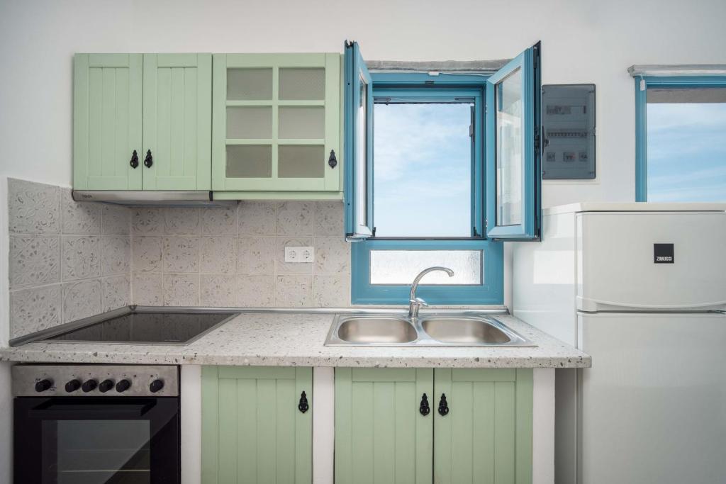 a kitchen with green cabinets and a sink and a window at Alcyone in Serifos Chora