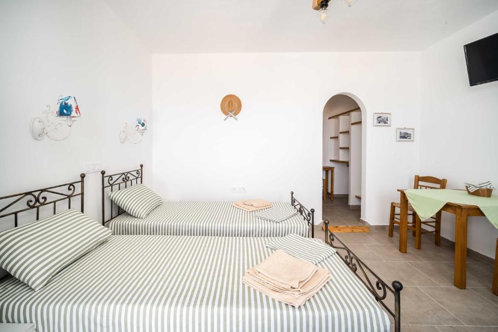 three beds in a room with a table and a table at Alcyone in Serifos Chora