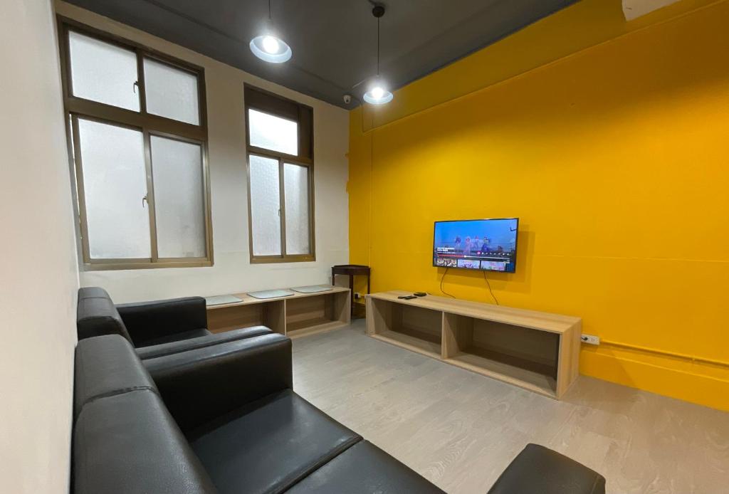 a living room with a couch and a tv on a yellow wall at 星空間 Star co-living space in Taipei