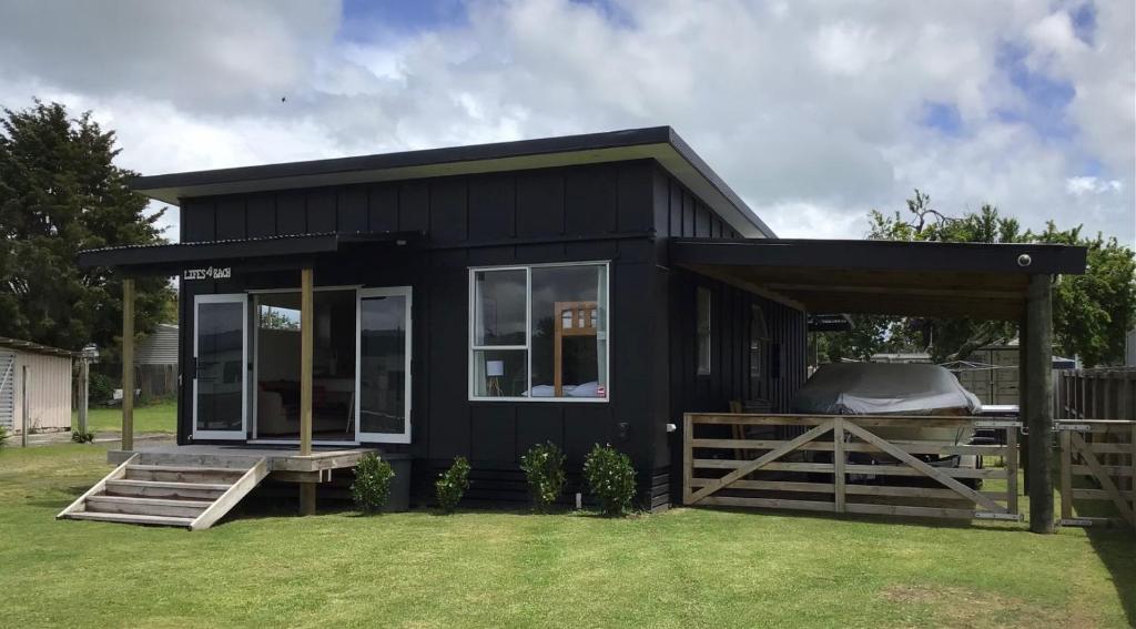 ein schwarzes winziges Haus mit einer Veranda und einem Zaun in der Unterkunft Black Beauty - Double Family Lake House for 12 with a NEW SPA & Pets in Mangakino