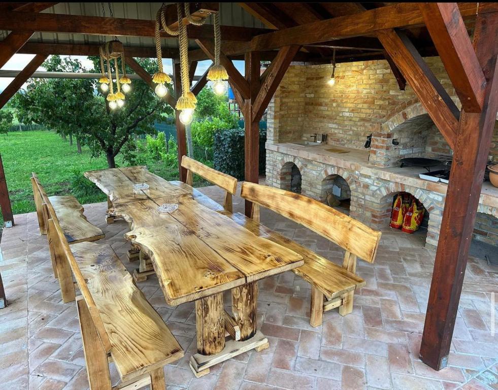 a wooden table and benches in a patio with an oven at Mila Vila, Fruška Gora in Irig