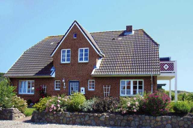 ein rotes Backsteinhaus mit einem Kacheldach in der Unterkunft Landtraum in Oevenum