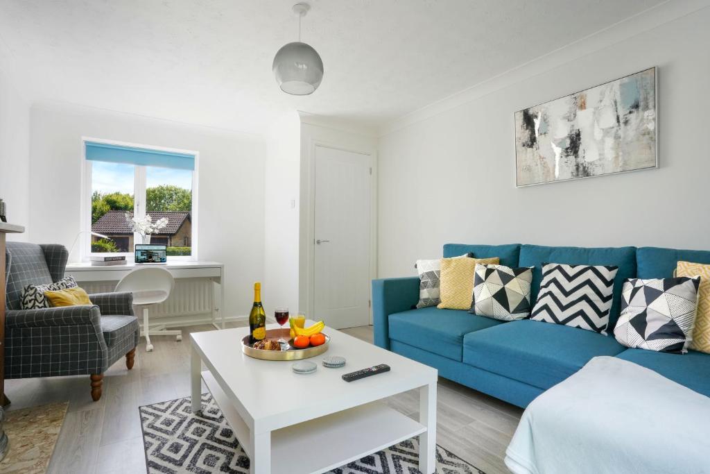a living room with a blue couch and a table at Detached House - Close to City Centre - Free Parking, Fast Wifi, Private Garden and Smart TV with Netflix by Yoko Property in Milton Keynes