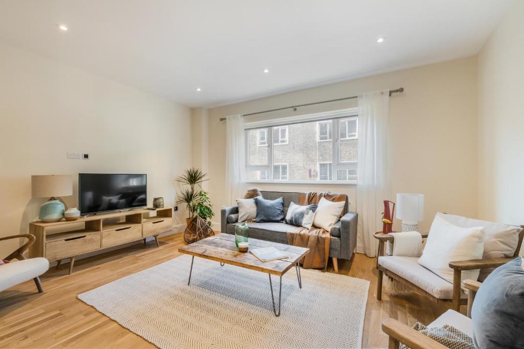 ein Wohnzimmer mit einem Sofa und einem Tisch in der Unterkunft StayLux Kensington in London