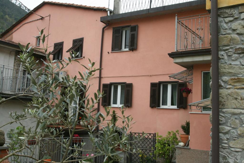 Una casa rosa con persianas negras. en Ca' Rossi, en Beverino