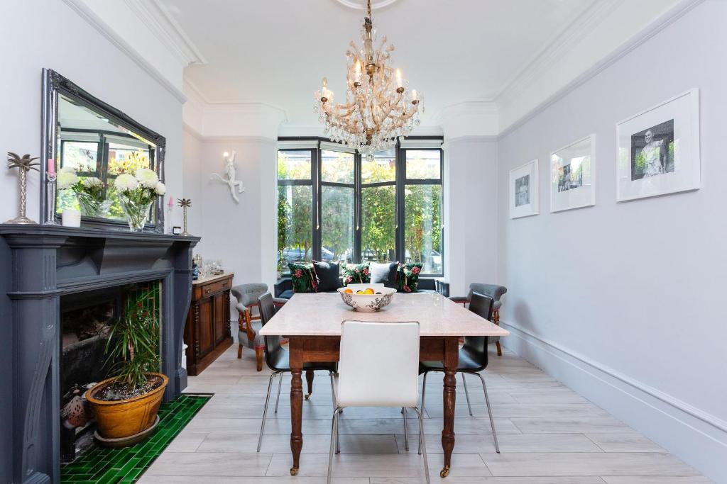 a dining room with a table and a fireplace at Veeve - Parkland Perfection in London