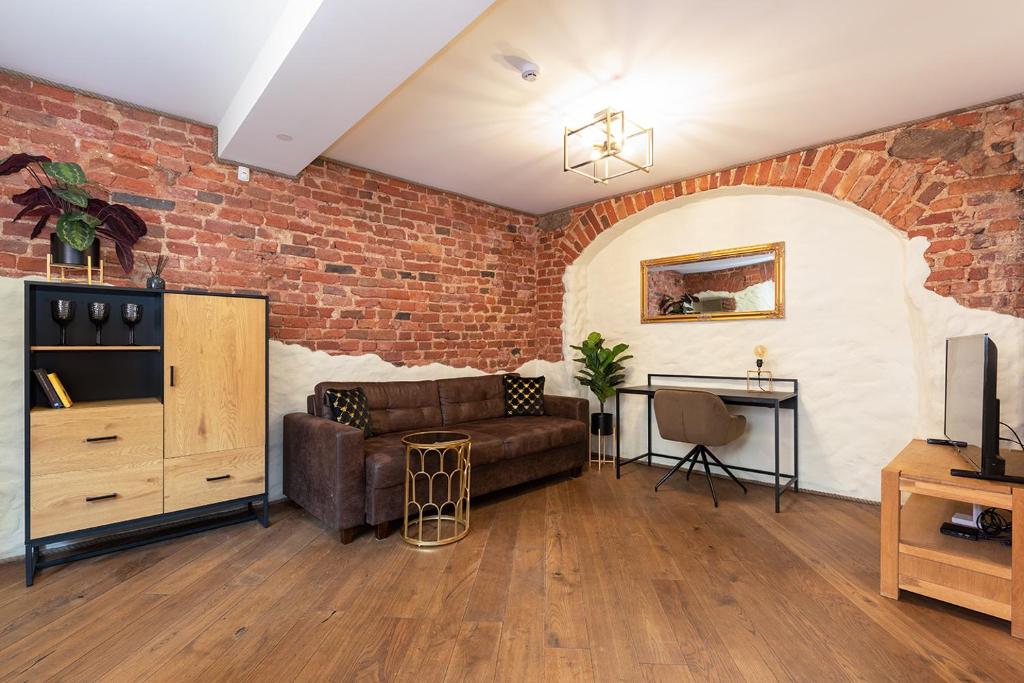 a living room with a couch and a brick wall at Rüütli Apartments in Tartu Old Town in Tartu