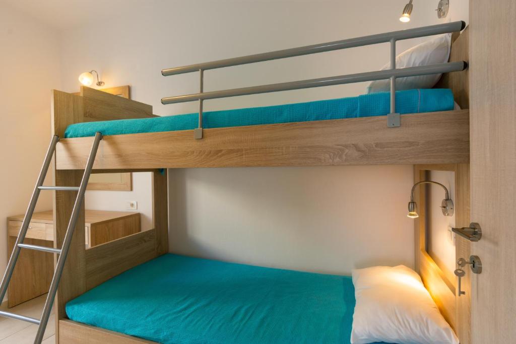 2 łóżka piętrowe w małym pokoju z niebieską pościelą w obiekcie Socrates Apartmens & Restaurant w mieście Milatos