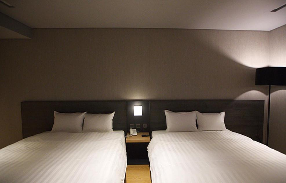 two beds in a hotel room with white sheets at Chiayi Guanzhi Hotel in Chiayi City