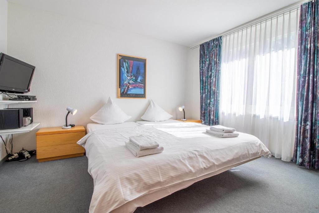 a bedroom with a large white bed and a window at Camana Wohnung EG in Arosa