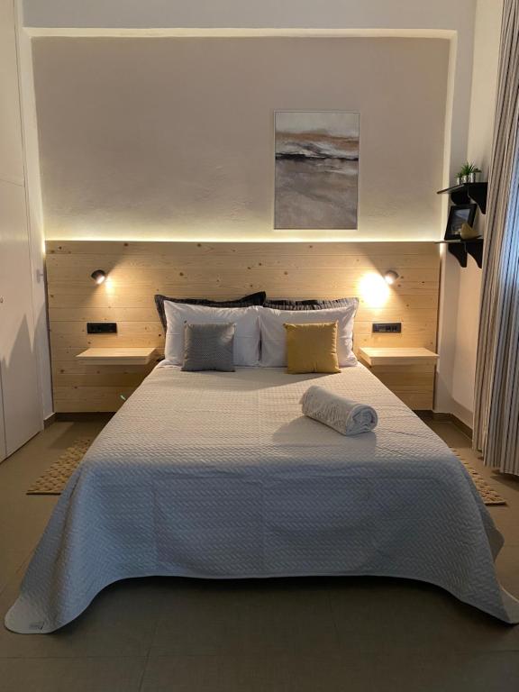 una camera da letto con un letto grande con lenzuola e cuscini bianchi di Tiny Square a Nafpaktos