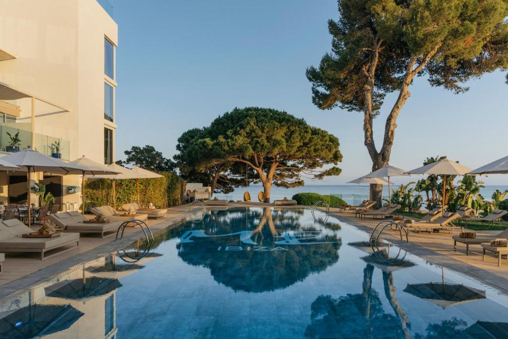 a swimming pool at a resort with chairs and umbrellas at ME Ibiza - The Leading Hotels of the World in Santa Eularia des Riu