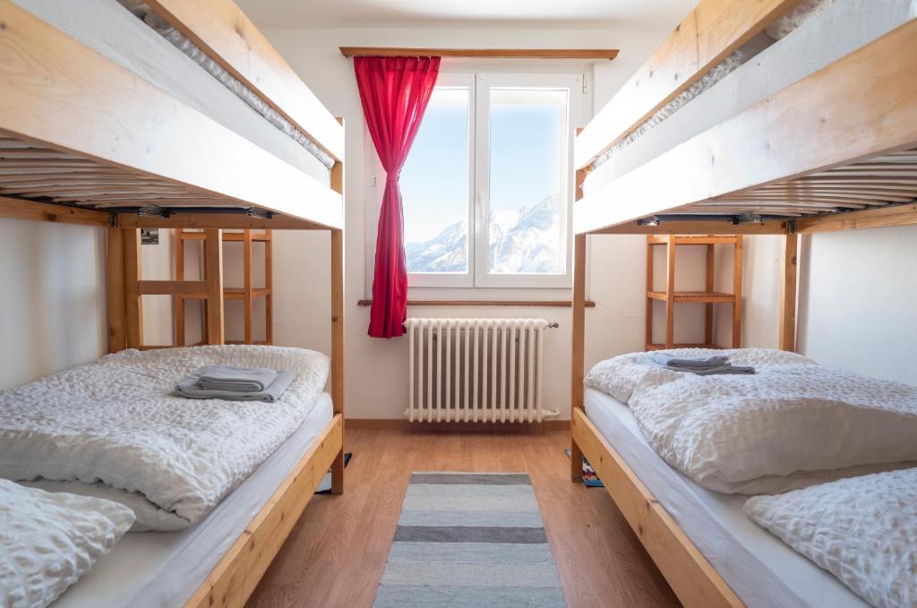 two beds in a room with a window at Hotel Schwarzsee in Zermatt