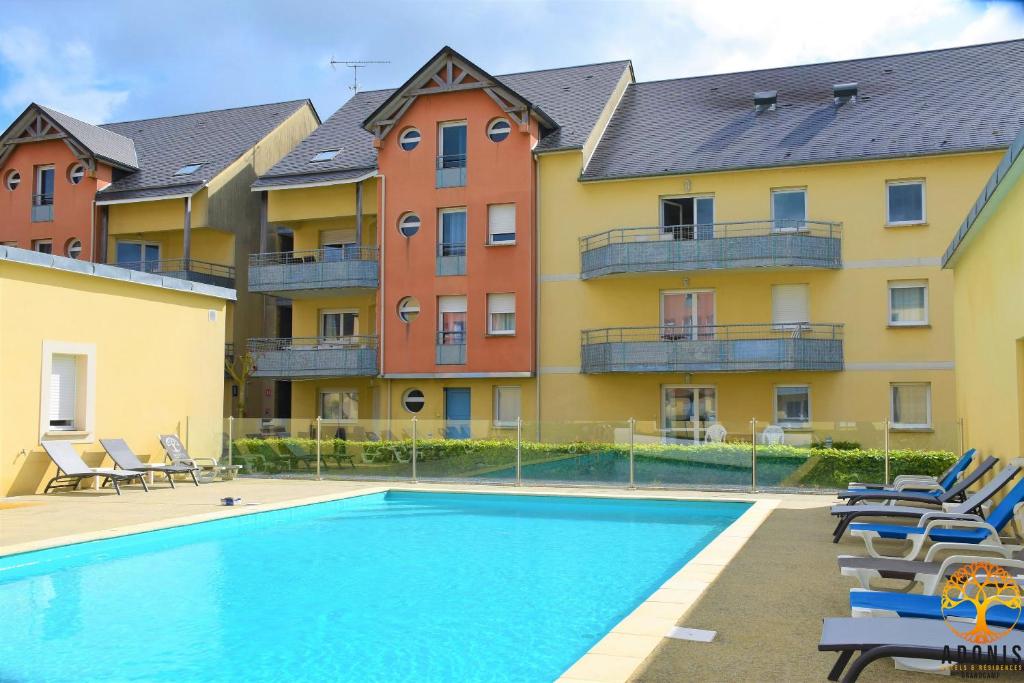 a swimming pool in front of a building at Adonis Grandcamp - Résidence Les Isles De Sola in Grandcamp-Maisy