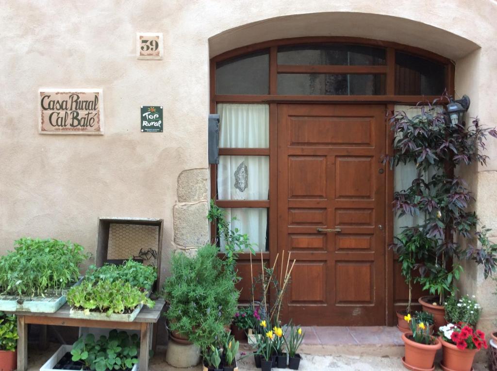 um edifício com uma porta de madeira e vasos de plantas em Casa Rural Cal Baté em Pratdip