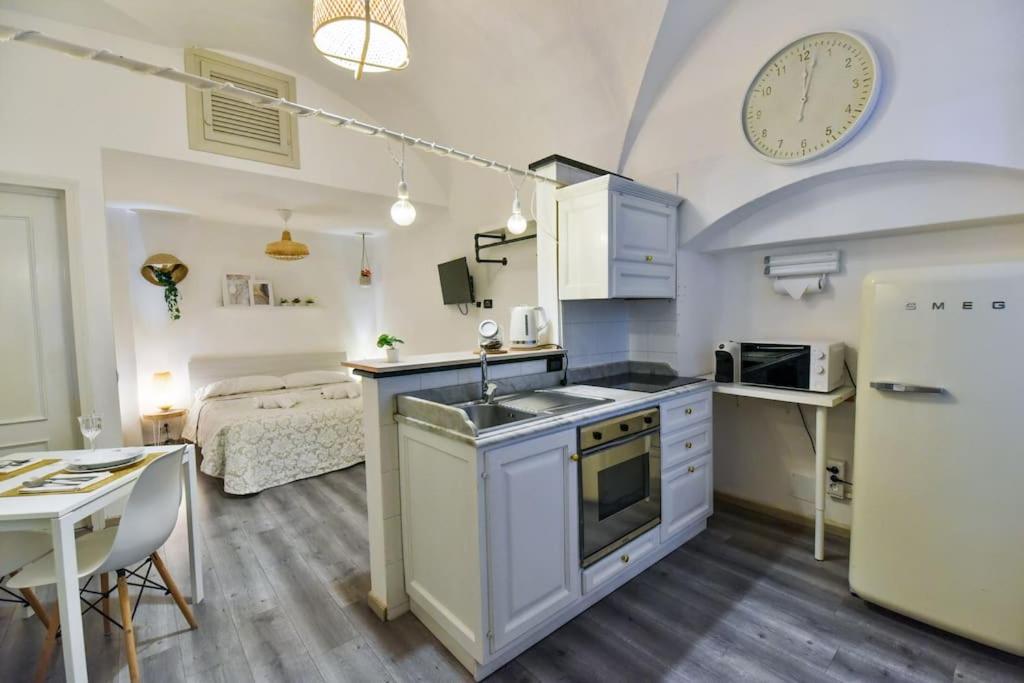 a kitchen with a sink and a refrigerator and a bed at Welcome Varigotti - Borgo Saraceno - Tramontana in Varigotti