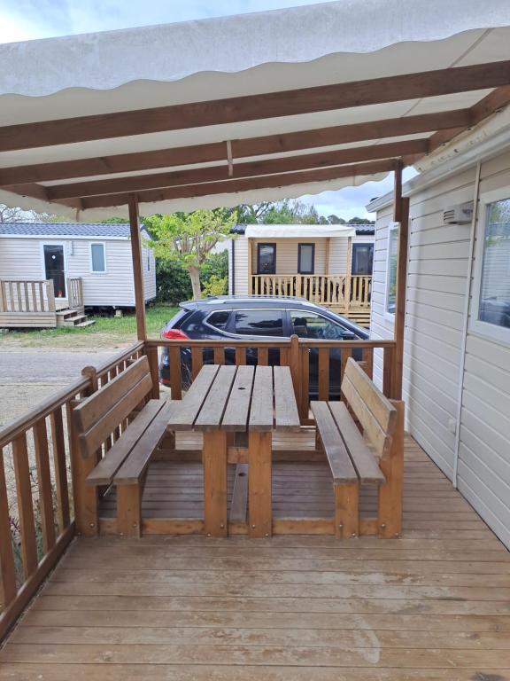 eine Holzterrasse mit einem Picknicktisch auf einem Haus in der Unterkunft Mobil Home (Clim, Tv)- Camping Narbonne-Plage 4* - 020 in Narbonne-Plage