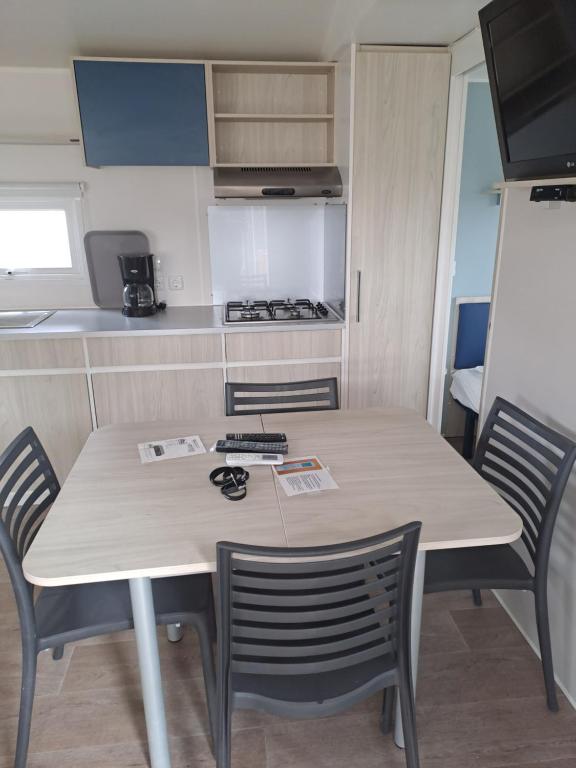 eine Küche mit einem Tisch und Stühlen in einem Wohnwagen in der Unterkunft Mobil Home (Clim, Tv)- Camping Narbonne-Plage 4* - 020 in Narbonne-Plage