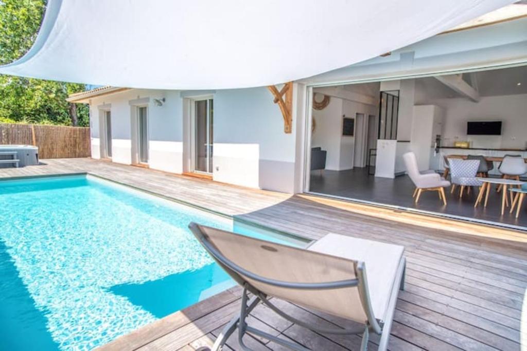 - une piscine avec une chaise et une maison dans l'établissement La villa Sirelis piscine et spa, à Gujan-Mestras