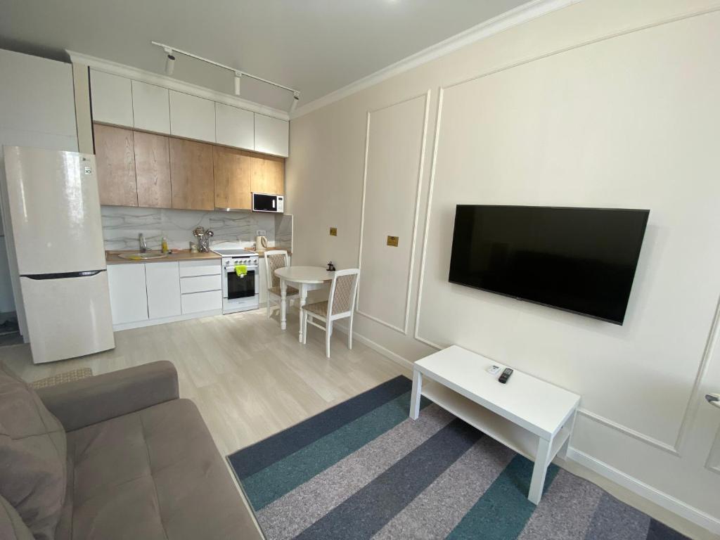un soggiorno con divano e TV a schermo piatto di Alau Apartments a Astana
