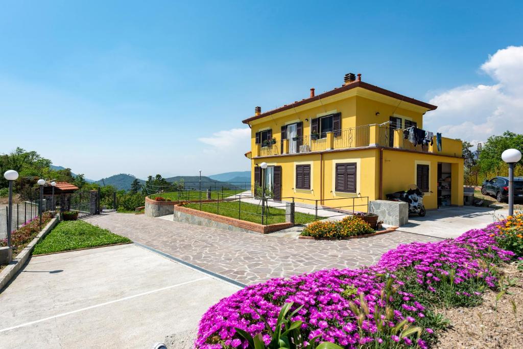 una casa amarilla con flores púrpuras delante de ella en ALTIDO Villa Guanna - Charming Flat with Garden en Bracco